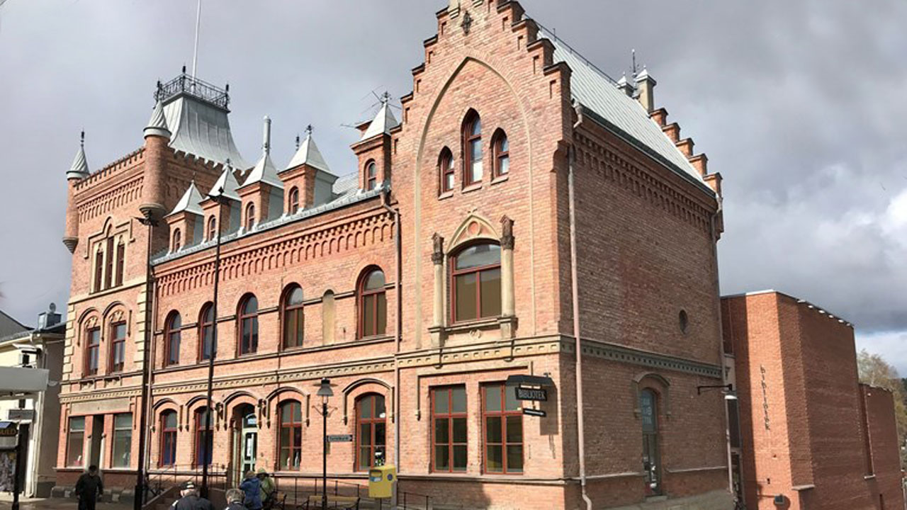 Apotekshuset från gågatan. Röd tegelfasad med tinnar och torn.