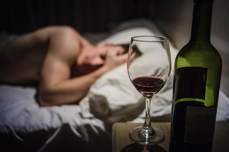 Vinglas, vinflaska, person i en säng