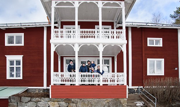 Familj på farstukvist till fint gammalt rött hus med vita detaljer